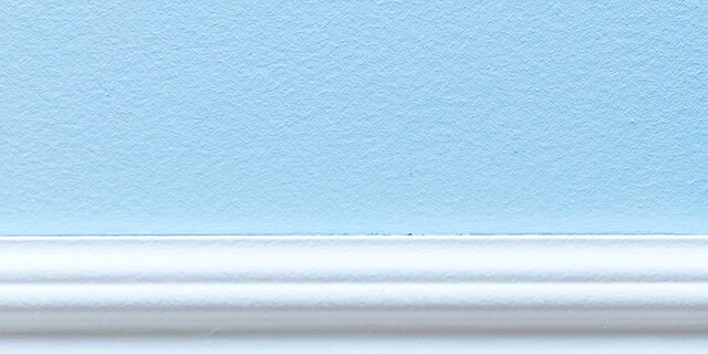 A white baseboard and light blue wall.
