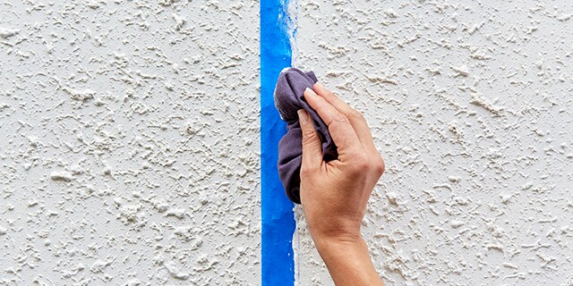 A person using a cloth to smooth out caulk on painter's tape.
