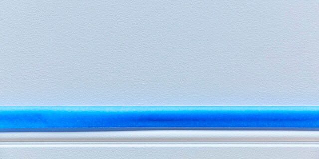 Blue painter's tape on a baseboard.
